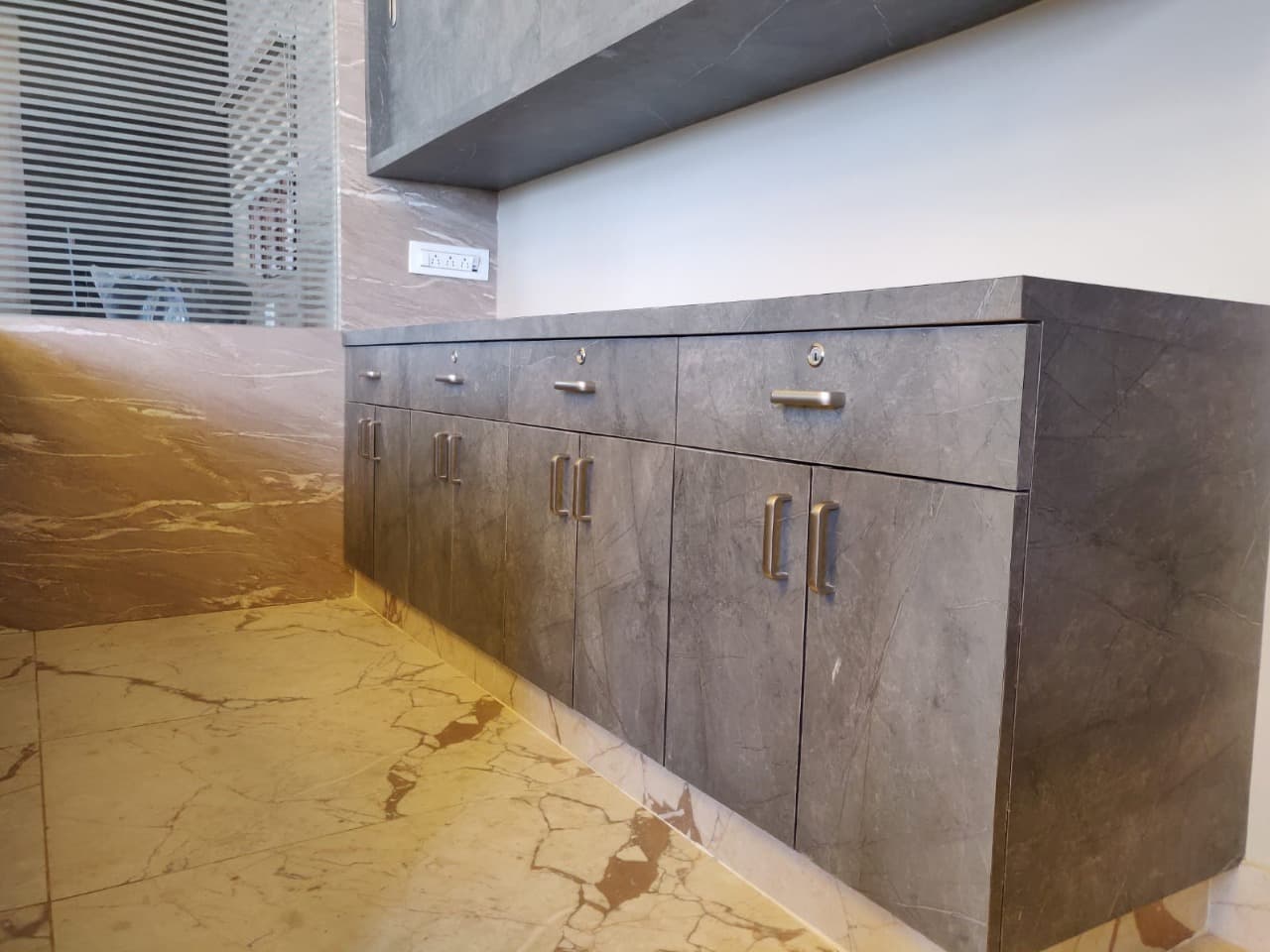 Marble-finish WPC unit with brushed brass handles, built for a damp-prone wall