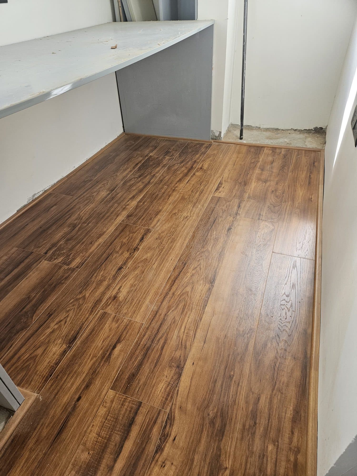 Laminate flooring finished against the wall with matching beading over the expansion gap