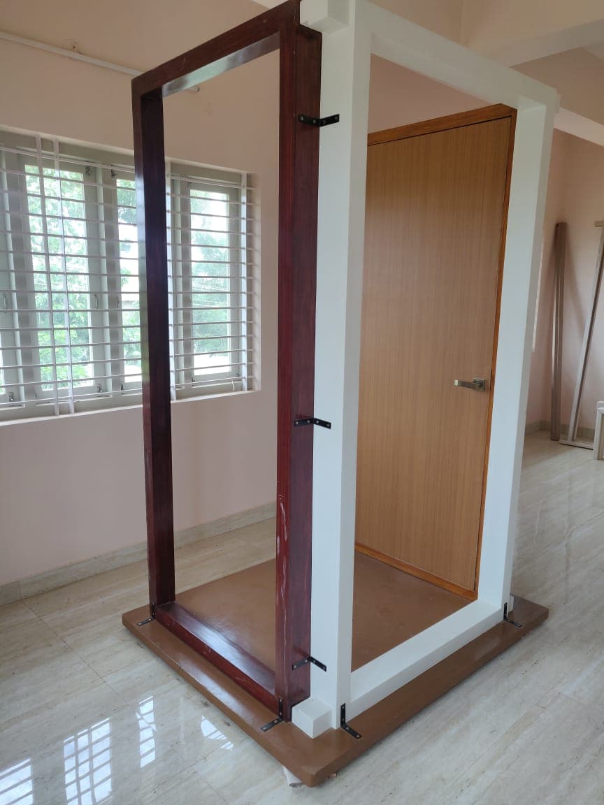 A finished door frame and shutter mounted on a display stand at Vishnu Timber Touch